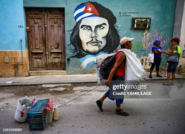 Man pulls plastic for recycling in front of a graffiti depicting Argentine-born revolutionary leader Ernesto "Che" Guevara, in a street of Havana, on...