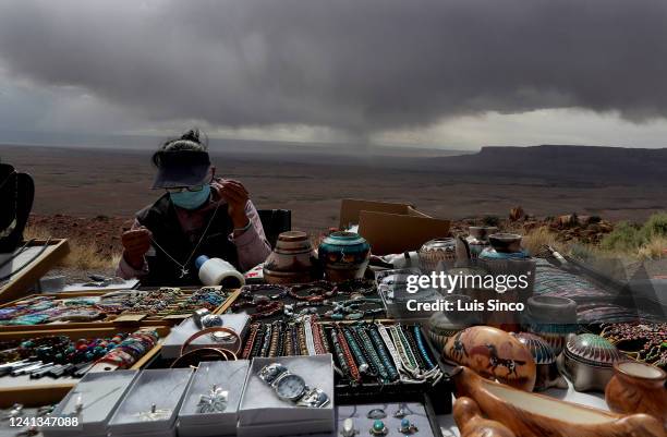 Storms clouds appear threatening but produce little rain as a Native American woman sells handmade jewelry from a stand along Highway 89 near Page....