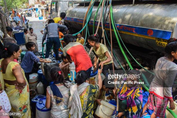 People fill water containers with drinking water from a Municipal Water Tanker outside a slum cluster in New Delhi. The demand for drinking water has...