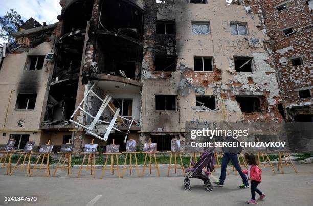 Woman and her daughter walk past a residential building destroyed as a result of shelling in town of Irpin, near the Ukrainian capital of Kyiv on...