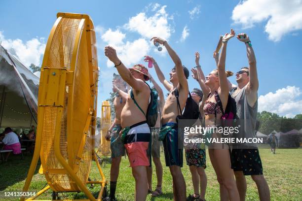 Festival goers attending the Bonnaroo Music and Arts Festival stand in front of giant misters in an attempt to stay cool in 100-degree heat on June...