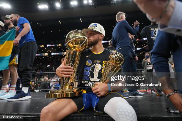 Stephen Curry of the Golden State Warriors celebrates on stage with The Larry O'Brien Trophy and the Bill Russell Finals MVP Trophy after winning...