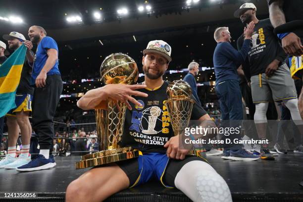 Stephen Curry of the Golden State Warriors celebrates on stage with The Larry O'Brien Trophy and the Bill Russell Finals MVP Trophy after winning...