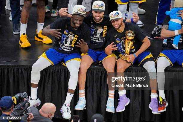 Draymond Green, Stephen Curry and Klay Thompson of the Golden State Warriors celebrate on stage with the Bill Russell Finals MVP Trophy after winning...