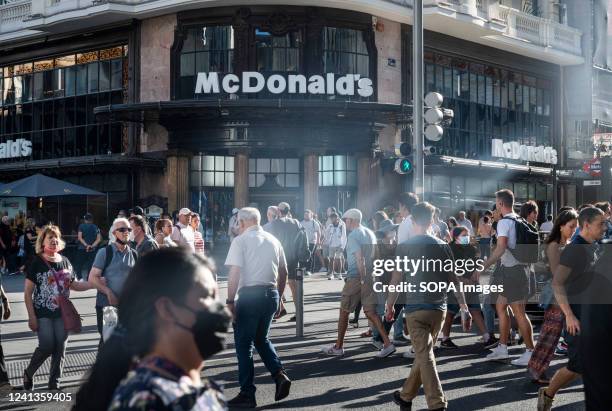 Pedestrians cross the street in front of the American multinational fast-food hamburger restaurant chain, McDonald's in Spain.