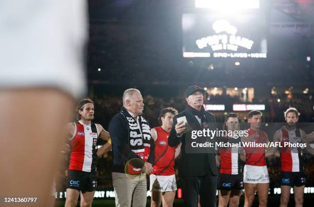 Players, coaches and umpires huddle as Tim Watson and Nathan Burke speak before Spuds Game during the 2022 AFL Round 14 match between the St Kilda...