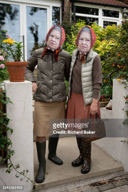 Two residents wear identical face masks and scarves to resemble the queen during a South London street party organised by the community, helping to...