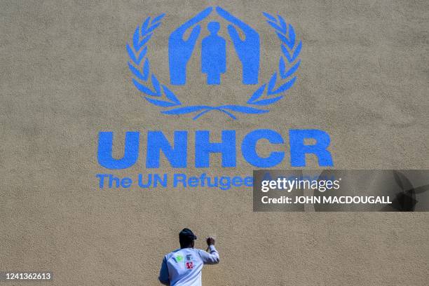 Workers dismantle a scaffolding after the completion of a giant mural featuring a logo of the UNHCR, on a residential building in northern Berlin on...