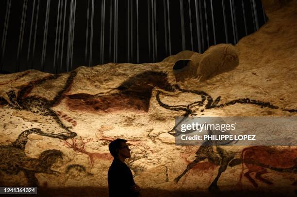 Vsitors looks at a section of the life size Lascaux cave replica after a special immersive torch light visit on June 16, 2022 in Montignac.