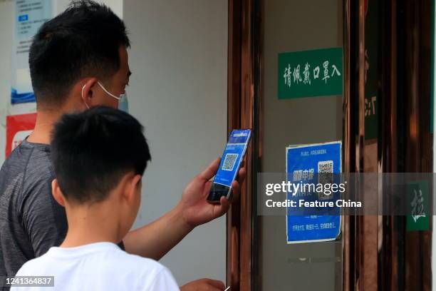 Man scans a QR code to present his Covid risk code before entering a shop in Zhengzhou city in central China's Henan province Friday, June 17, 2022....