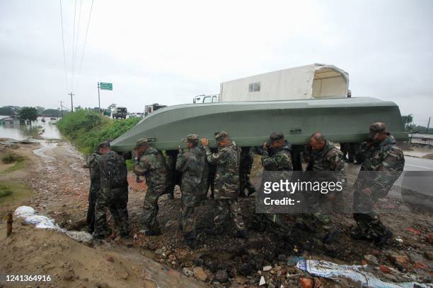 Army personnel carry a boat during a rescue operation to evacuate people from a flooded area following heavy monsoon rainfalls on the outskirts of...