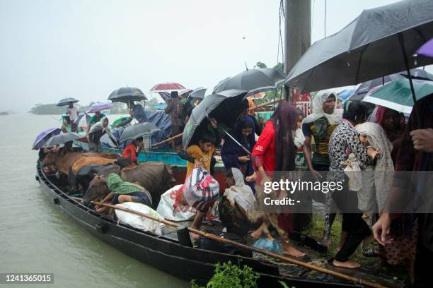 People prepare to get of a boat after being evacuated from a flooded area following heavy monsoon rainfalls on the outskirts of Sylhet on June 17,...