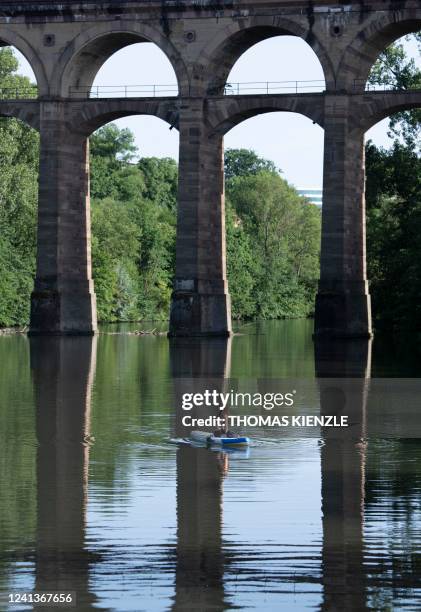 Woman enjoys the evening sun on her paddle board under the Enztal Viaduct on the Enz River in Bietigheim-Bissingen, southern Germany, on June 17,...