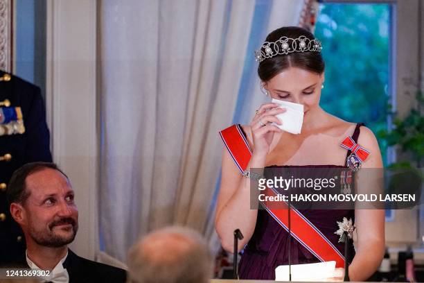 Norway's Princess Ingrid Alexandra reacts next to her father, Norway's Crown Prince Haakon, as she delivers a speech during a gala dinner for her...
