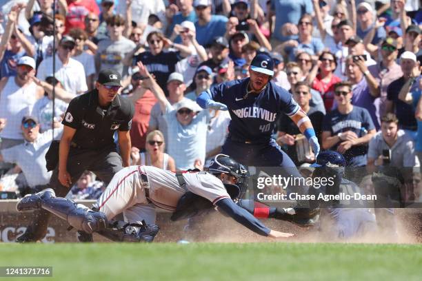 Travis d'Arnaud of the Atlanta Braves reaches for Jonathan Villar of the Chicago Cubs as he crosses home plate to score the game winning run in the...