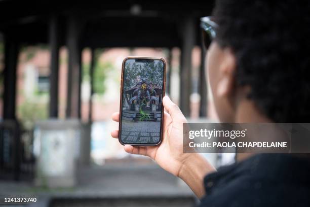 Man looks for 3D virtual artworks using the dedicated app during the Mural festival in Montreal, Quebec on June 16, 2022. - A mysterious creature...