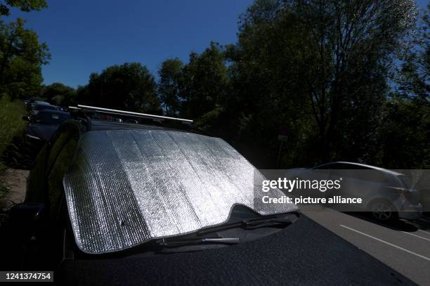 June 2022, Bavaria, Inning: A sunshade lies on the windshield of a car parked in the sun. Events will be held to draw attention to the dangers of...