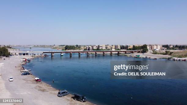 An aerial view shows Syrians gathering on the bank of the Euphrates River in the northern city of Raqa on June 17, 2022.