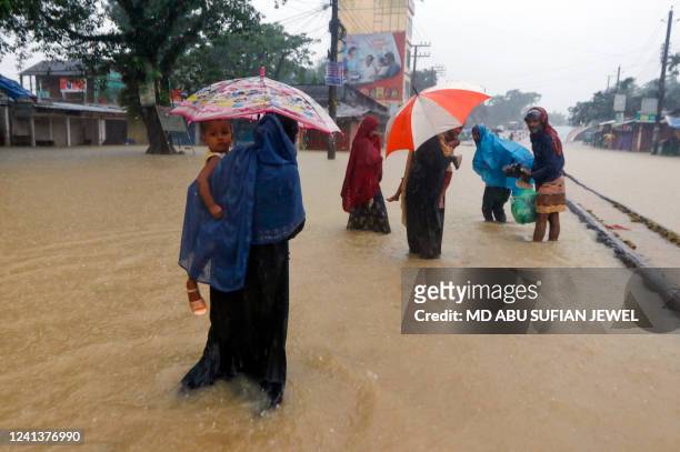 People wade along a road in a flooded area following heavy monsoon rainfalls in Sylhet on June 18, 2022. Monsoon storms in Bangladesh have killed at...