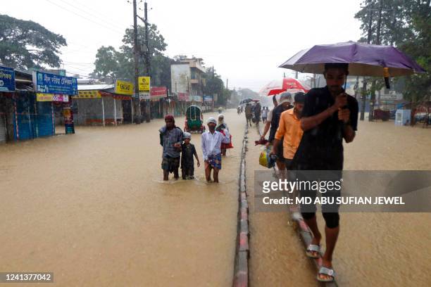 People wade along a road in a flooded area following heavy monsoon rainfalls in Sylhet on June 18, 2022. Monsoon storms in Bangladesh have killed at...