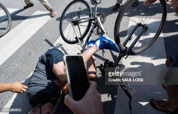 President Joe Biden falls off his bicycle as he approaches well-wishers following a bike ride at Gordons Pond State Park in Rehoboth Beach, Delaware,...