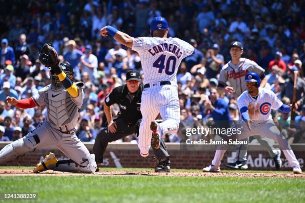 Willson Contreras of the Chicago Cubs beats the throw to home plate to score a run in the first inning as catcher William Contreras of the Atlanta...