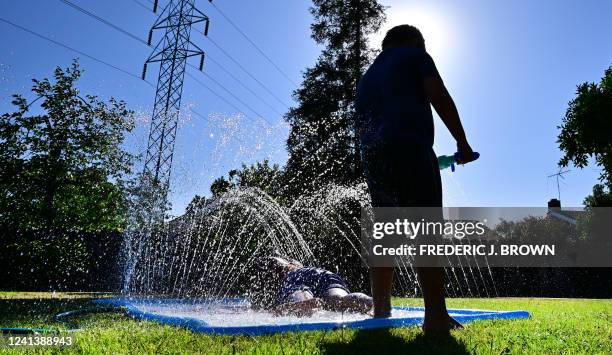 Children cool off on a lawn sprinkler toy in Fresno, California, on June 17, 2022. Millions of Americans have been under some sort of a heat advisory...