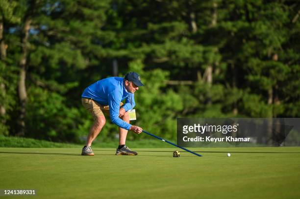 Member of the agronomy rolls a ball with a stimpmeter to measure the speed of a green during practice for the U.S. Open at The Country Club on June...
