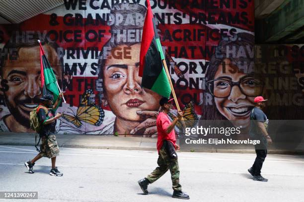 People hold up Pan-African flags while marching in the Juneteenth Atlanta Black History parade on June 18, 2022 in Atlanta, Georgia. Juneteenth, or...
