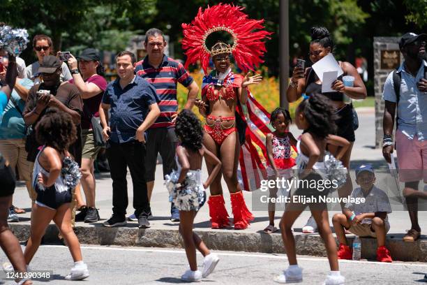 Woman in a costume and headdress waves at dancers marching in the Juneteenth Atlanta Black History parade on June 18, 2022 in Atlanta, United...