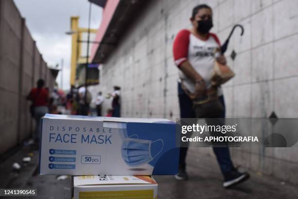 Woman walks by a shop selling protective masks at the San Salvador Historical Center on June 18, 2022 in San Salvador, El Salvador. The Health...