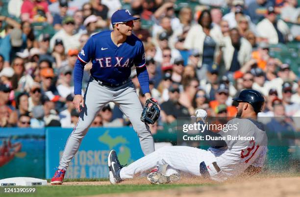 Riley Greene of the Detroit Tigers slides safe into third base with Brad Miller of the Texas Rangers covering the bag to advance on a sacrifice fly...