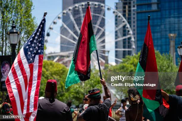 People raise American and Pan-African flags while marching in the Juneteenth Atlanta Black History parade on June 18, 2022 in Atlanta, United...