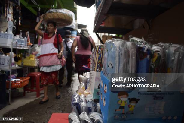 Woman walks by a shop selling protective masks at the San Salvador Historical Center on June 18, 2022 in San Salvador, El Salvador. The Health...