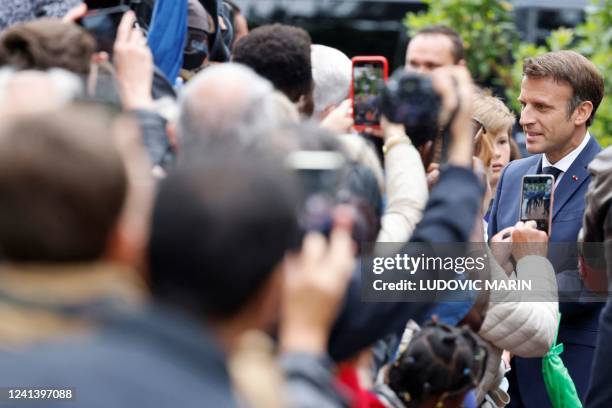 France's President Emmanuel Macron speaks to onlookers as he arrives to vote in the second stage of French parliamentary elections at a polling...