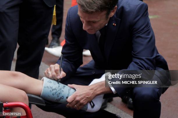 French President Emmanuel Macron signs a boys leg plaster as he arrives to vote in the second stage of French parliamentary elections at a polling...