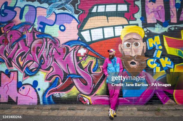 Artist 'Micky' alongside his new mural, which includes a self-portrait, created in an old railway arch that features in the Yardworks Festival 2022...