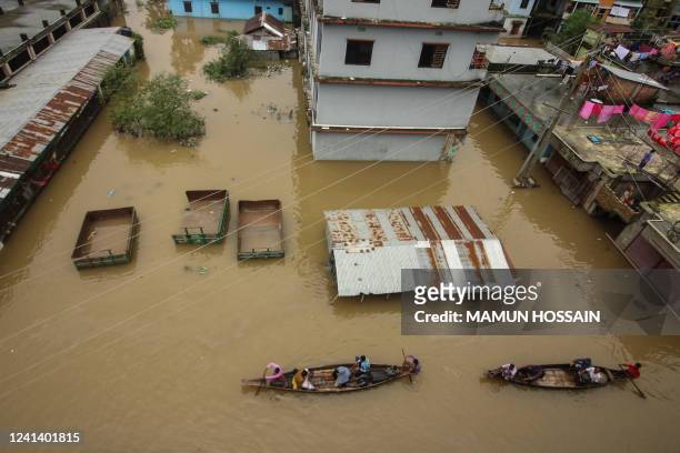 People use boats to wade through a road in a flooded area following heavy monsoon rainfalls in Companiganj on June 19, 2022.