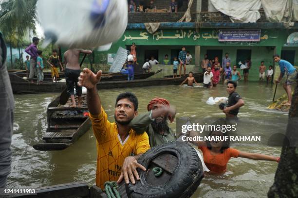 People collect food aid in a flooded residential area following heavy monsoon rainfalls in Companiganj on June 20, 2022. At least 26 more people have...