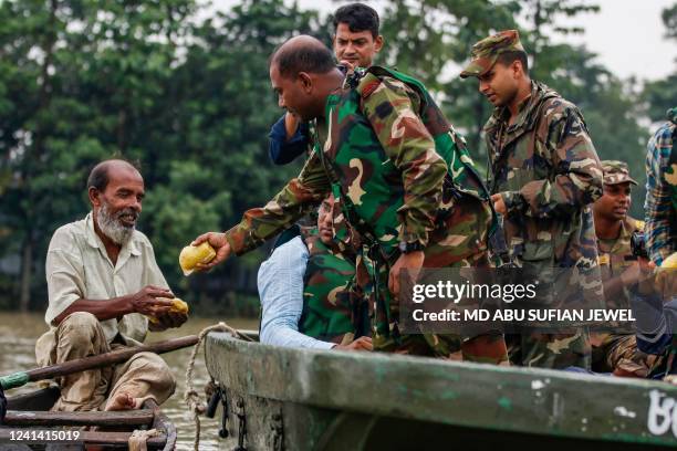 Man receives food aid from Bangladesh army in a flooded residential area following heavy monsoon rainfalls in Sunamganj on June 20, 2022. At least 26...