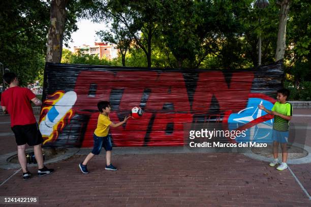 Children play next to a banner with the words "No to NATO" during a protest in Vallecas neighborhood of Madrid. Spain will host a NATO Summit in...