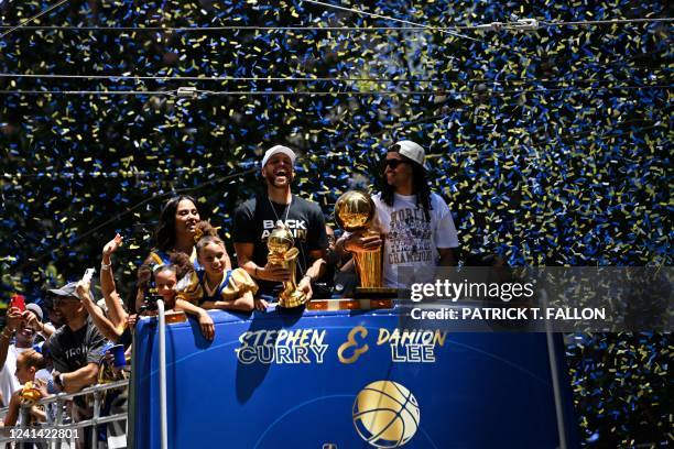 Basketball player Stephen Curry holds the MVP trophy alongside teammate Damion Lee as they celebrate from a double decker bus during the Golden State...