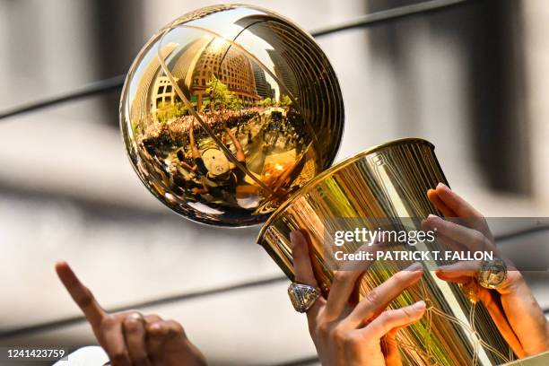 Otto Porter Jr. And Klay Thompson hold a trophy as they wave from a double decker bus while basketball fans cheer during the Golden State Warriors...