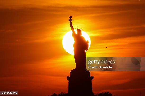 Sunset view with clouds behind the Statue of Liberty is seen from Brooklyn in New York City, United States on June 20, 2022.