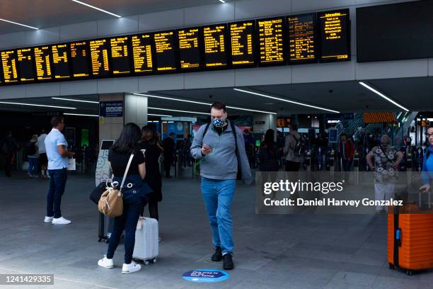 Pedestrians, some with luggage and some without, come and go under the digital timetables at the city's main train station as members of the RMT rail...