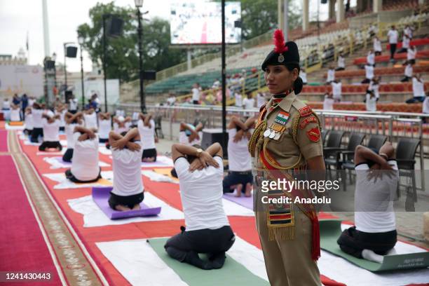 An Indian Border Security Force personal stands alert as participants perform Yoga during a special event held on the occasion of International Day...