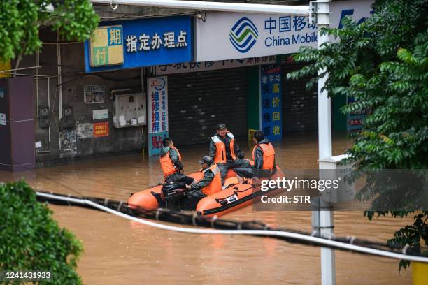 Rescue workers ride on a boat as they check a flooded street after heavy rains in Shaoguan in China's southern Guangdong province on June 21, 2022. -...