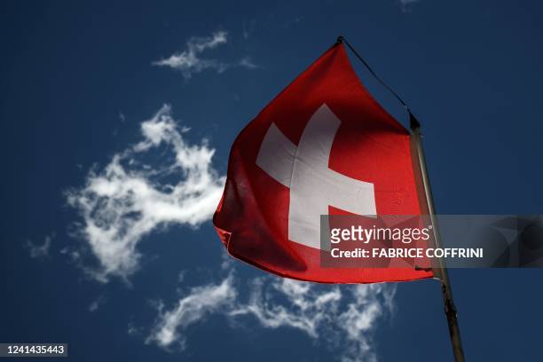 Swiss national flag flutters in a blue sky in Bourg-Saint-Pierre, western Switzerland on June 21, 2022.