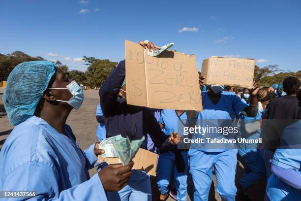 Doctors and Nurses protest whilst holding placards and the local currency which they are protesting against demanding their salaries in USD at...