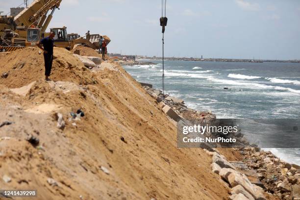 Palestinian construction workers build a seawall, from the rubble of building, to counter the coastal erosion near the al-Shati camp for Palestinian...